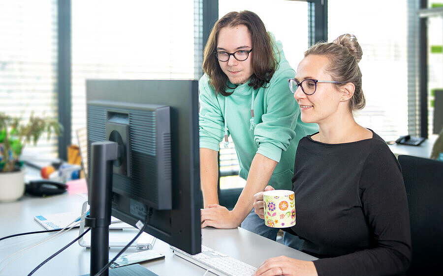 Mann und Frau besprechen Informationen am Schreibtisch und schauen auf den Bildschirm