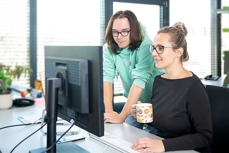 Mann und Frau besprechen Informationen am Schreibtisch und schauen auf den Bildschirm