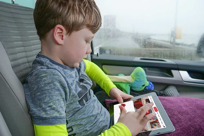 Junge sitzt im Auto und benutzt ein Tablet